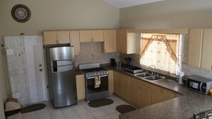 A compact kitchen with a refrigerator, stove, sink, and microwave. - Your Holiday Home Caribbean Estates (Portmore)