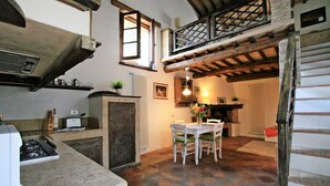 Une cuisine rustique avec un plan de travail en pierre, une cuisinière et un coin repas comprenant une table et des chaises.