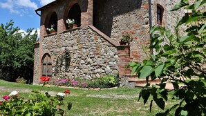 Un bâtiment rustique en pierre, doté d’une porte en bois et de fenêtres en arc de cercle.