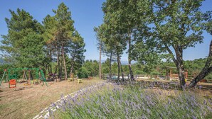 A playground with swings and a slide, surrounded by trees and lavender fields. - Beautiful home in Monte San Savino -AR- (Monte San Savino -AR-)