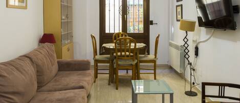 Cozy living space with a sofa, dining area, and large window offering a view of the outside.