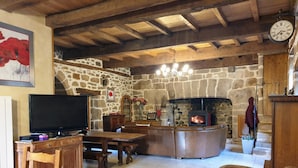 A rustic interior with a stone wall, wooden furniture, a fireplace, and a clock.