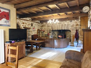 A rustic interior with a stone wall, wooden furniture, a fireplace, and a clock.