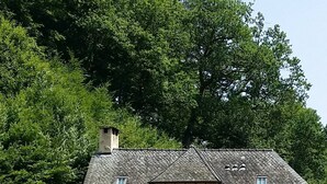 A stone building with a sloped roof and wooden garden beds in front.