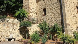 A stone building with a tower, a bench, and a small garden area.