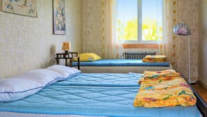 A room with two beds, a radiator, a window with curtains, and a lamp on a side table. - 4 bedroom stunning home in Mariannelund (Mariannelund)