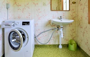 Et lille badeværelse med en Bosch vaskemaskine, vask og toilet.