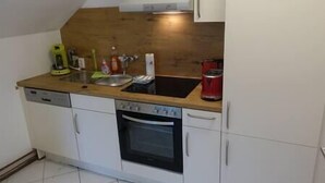 Een kleine keuken met een vaatwasser, oven, spoelbak en een houten aanrecht.