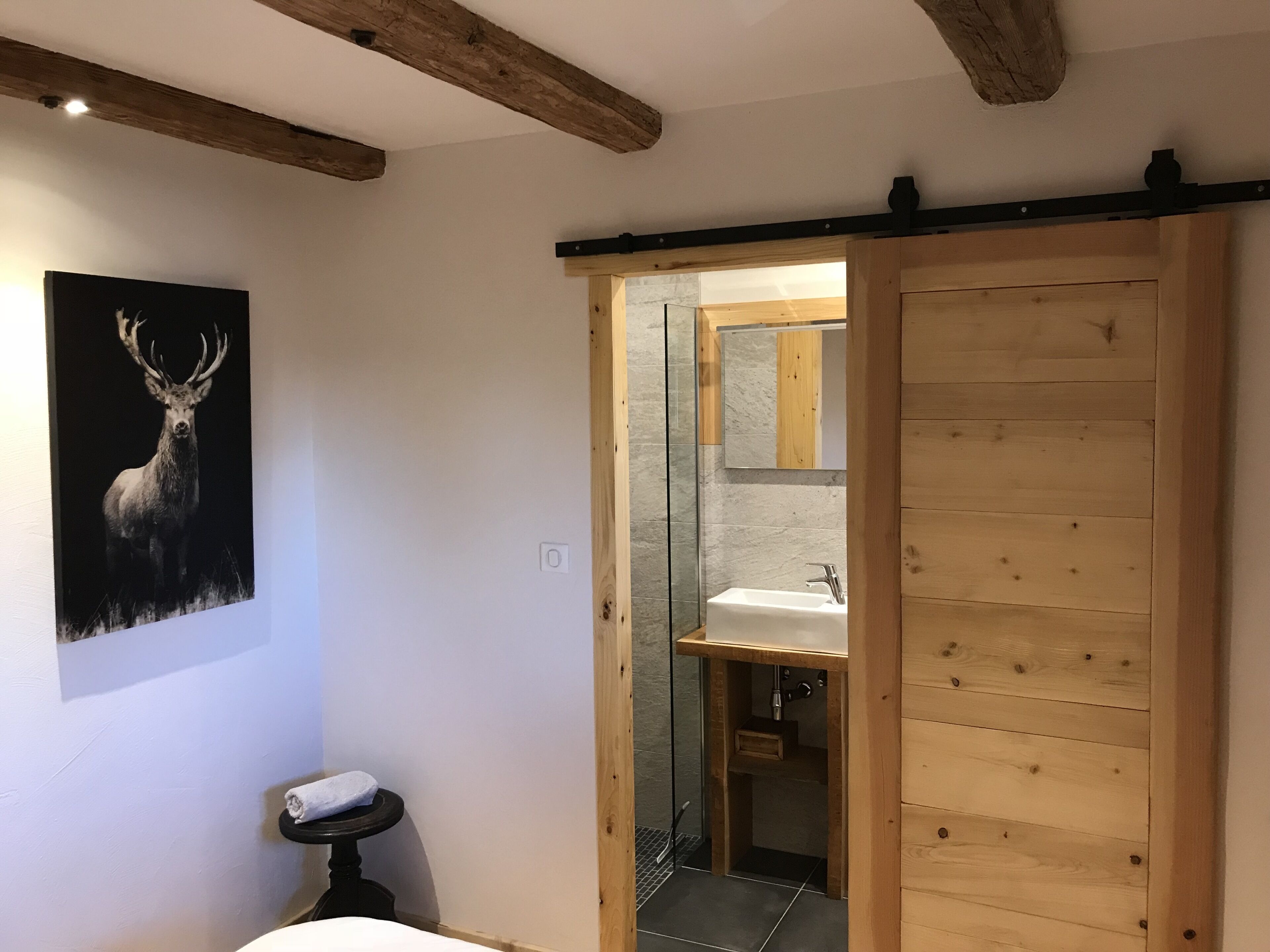 A bathroom with a wooden door, a sink, and a mirror.