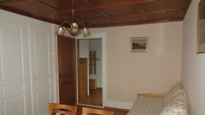Quarto com teto de madeira, uma cama com roupa de cama floral, uma cadeira de madeira e uma pequena mesa de cabeceira.