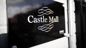 Ein schwarzes Schild mit dem Schriftzug 'Castle Mall' und einem dekorativen Symbol.