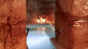 A spa area with a pool, two wall-mounted lanterns, and a stone wall. - Musae Relais & Spa (Polignano a Mare)