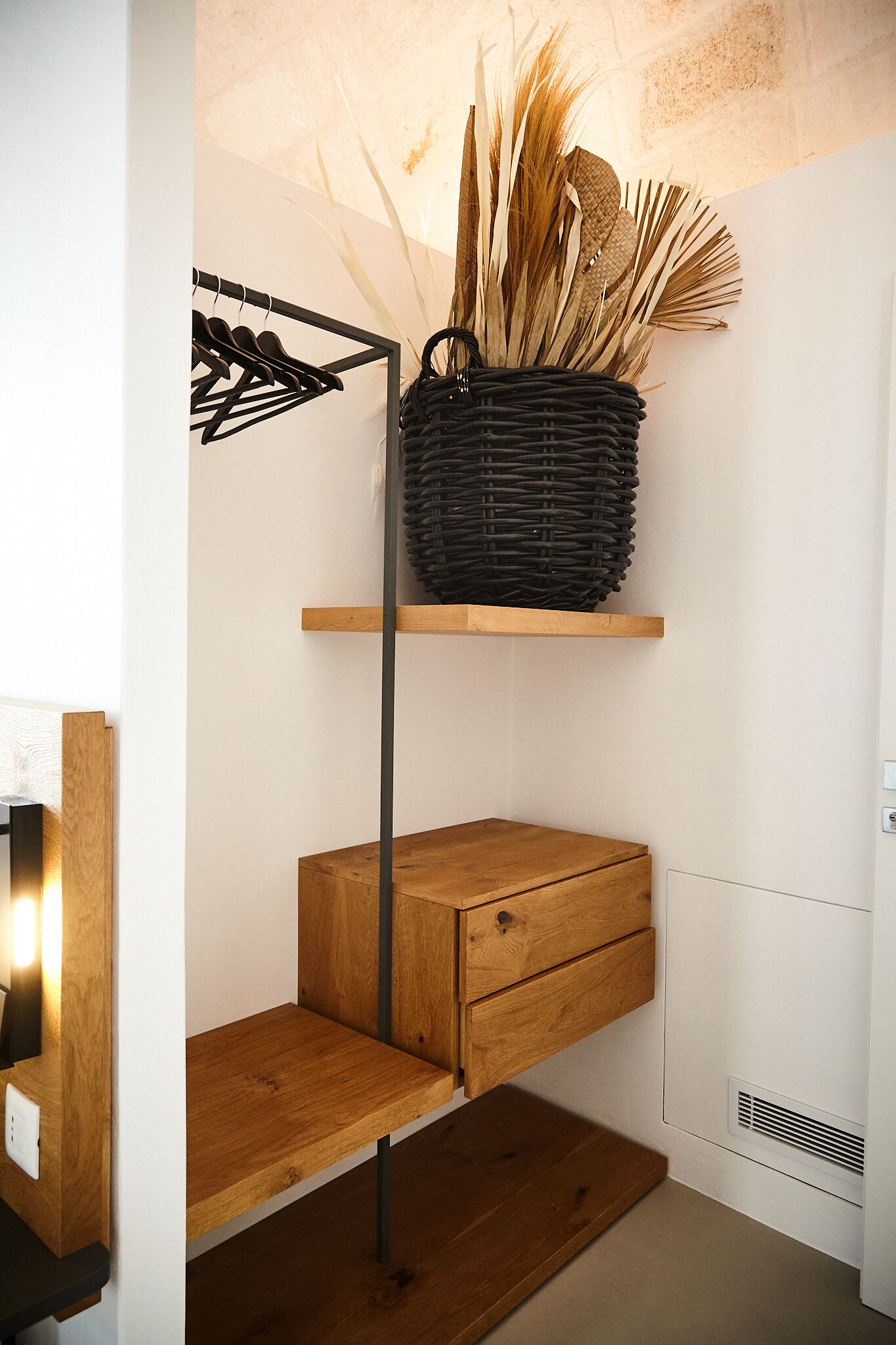 A wooden shelf with a woven basket containing dried plants.