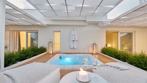 A modern outdoor pool area with a hot tub, lounge chairs, and a candle on a table. - Musae Relais & Spa (Polignano a Mare)