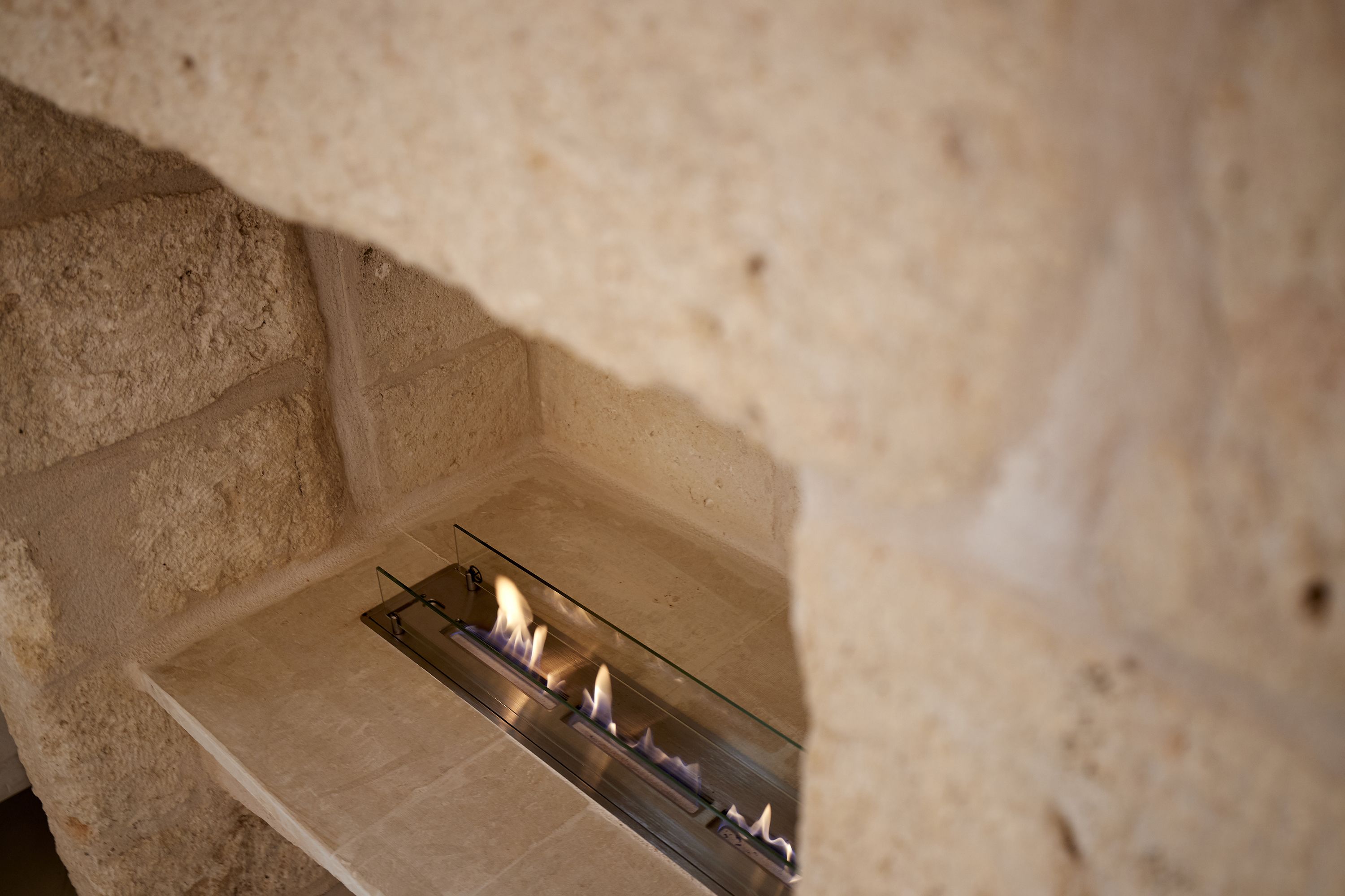 Une cheminée en pierre avec une étagère en verre et un foyer en métal.