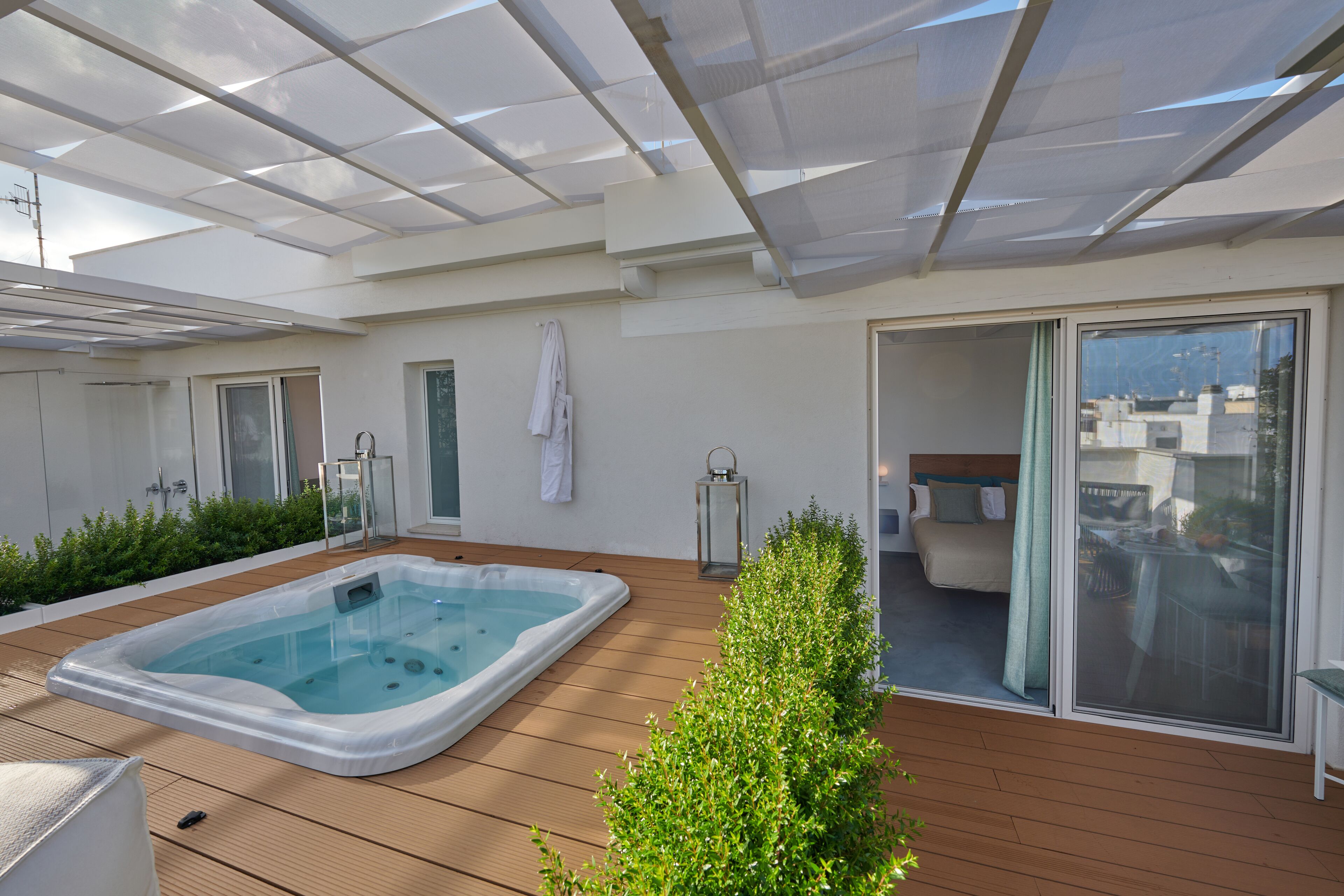 Terraza en la azotea con jacuzzi, deck de madera y puerta de cristal que da a un dormitorio.