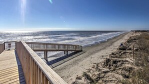 En träpromenad som leder till en strand med fri utsikt över havet.