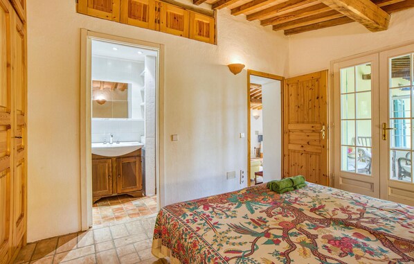 Un dormitorio con cama, un baño con lavamanos y techo de madera.