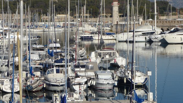 A marina with numerous boats docked, a prominent castle in the background, and calm water reflecting the boats. - Apartment near sea and city (Antibes)