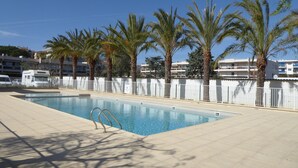 An empty swimming pool with a white fence, palm trees, and a clear blue sky. - Apartment near sea and city (Antibes)