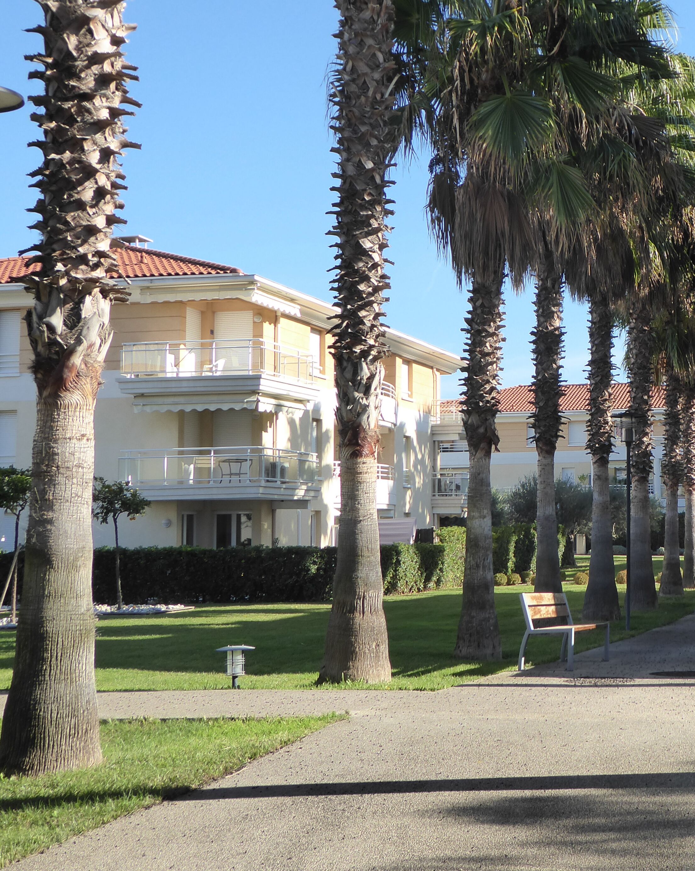 Un edificio con balcón y palmeras al frente.
