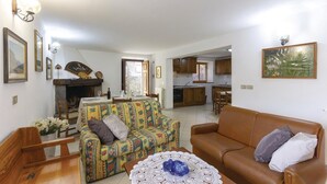 A living room with a sofa, a coffee table, and a fireplace. There is a kitchen visible in the background. - Gorgeous home in Sassalbo -MS- (Sassalbo -MS-)
