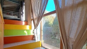 A staircase with colorful steps leading to a window with curtains. - SMALL GITE "BERGERIE" (Bargeme)