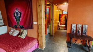 A room with a bed, a wooden table with artwork, and a tapestry. - SMALL GITE "BERGERIE" (Bargeme)