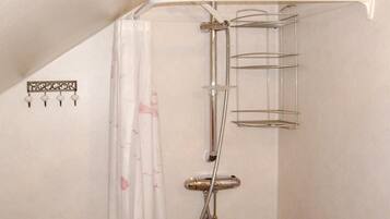 Une douche équipée d’une étagère en métal et d’un porte-serviettes fixé au mur.