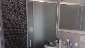 A bathroom with a shower, a sink, and a mirror.