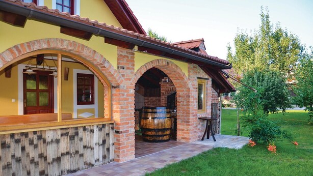 Ein Haus mit Backsteinfassade, einem Holzfass und einem kleinen Garten.