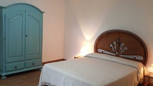 A bedroom with a bed, a nightstand, a lamp, and a wardrobe.