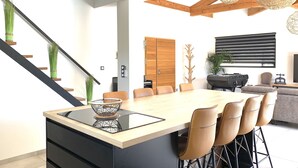 A modern dining area with a large wooden table, black chairs, and a central island with a black tray. - Pool Villa Near Beach (Agde)