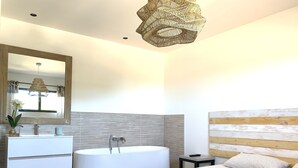 A modern bathroom with a freestanding bathtub, a large mirror, and a wooden headboard. - Pool Villa Near Beach (Agde)