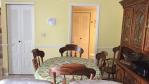 Ein Esszimmer mit Tisch, gedeckt für vier Personen, flankiert von Holzstühlen, einem Holzschrank und einer Wanduhr.