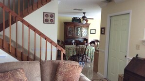 Ein Wohnzimmer mit einer Holztreppe, einem Essbereich mit Tisch und Stühlen sowie einer Tür.