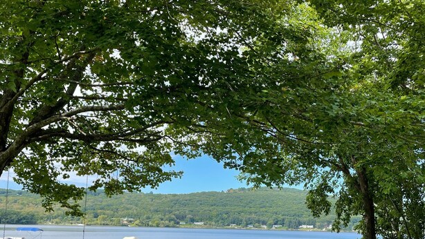 A lakeside view with a swing chair, docked boats, and a stone wall. - Lakefront Cozy Cottage  (Rockport)