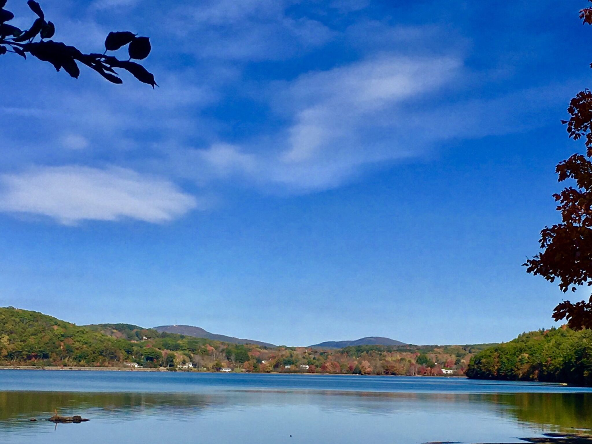 Ein ruhiger See unter einem klaren Himmel, in der Ferne sanfte Hügel.