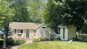 A residential property with a well-maintained lawn, a small shed, and a house with a front porch. - Lakefront Cozy Cottage  (Rockport)