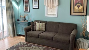 A cozy living room with a brown sofa, a patterned rug, and a teal wall. - Lakefront Cozy Cottage  (Rockport)