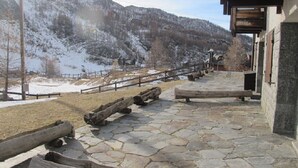 Un sentier pavé de pierres menant à un bâtiment entouré d’une clôture en bois, avec une chaîne de montagnes en arrière-plan.