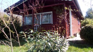 Ein rotes Holzhaus mit Satteldach und einer Veranda.