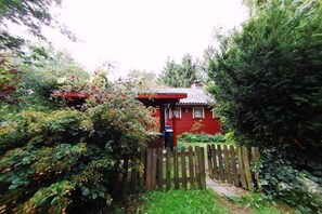 Una casa rossa con una recinzione di legno e una cassetta delle lettere.