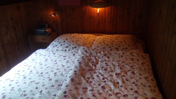 Ein Zimmer mit Holzboden und einem Bett mit floralem Bettzeug.