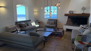 Un salón espacioso con un ventanal grande, chimenea y vistas al océano.