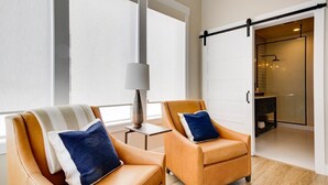 A modern room with two leather armchairs, a small table with a lamp, and a sliding door leading to a bathroom. - Casa Grosgrain-Gorgeous views, On-Site winery (Walla Walla)