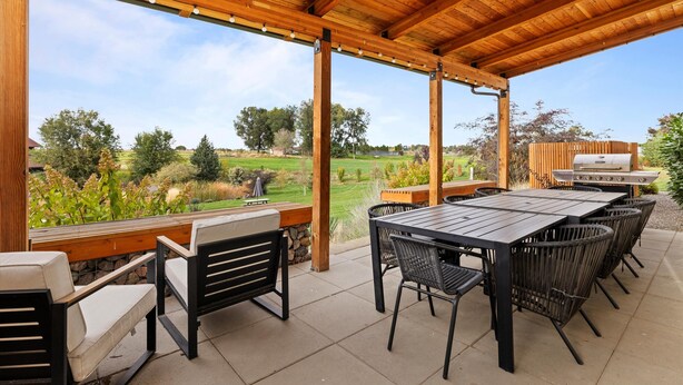 An outdoor patio with a wooden pergola, a table and chairs, and a grill in the background. - Casa Grosgrain-Gorgeous views, On-Site winery (Walla Walla)
