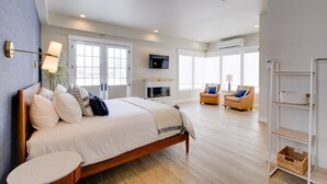 A spacious bedroom with a large bed, a TV, a fireplace, and a seating area with two chairs. - Casa Grosgrain-Gorgeous views, On-Site winery (Walla Walla)