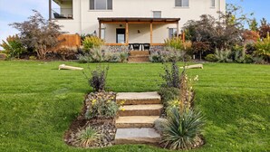 A two-story house with a covered porch, stone steps leading to the entrance, and a well-maintained lawn. - Casa Grosgrain-Gorgeous views, On-Site winery (Walla Walla)