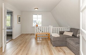 A room with a wooden floor, a gray sofa, a white railing, and a window with a view. - Stunning home in Hultsfred with sauna (Hultsfred)